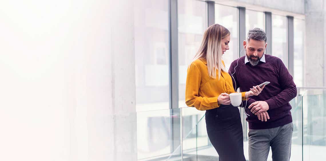 attractive male and female sales professionals looking on a smart phone to review an account plan they learned how to create in richardson's prosperous account strategy training program