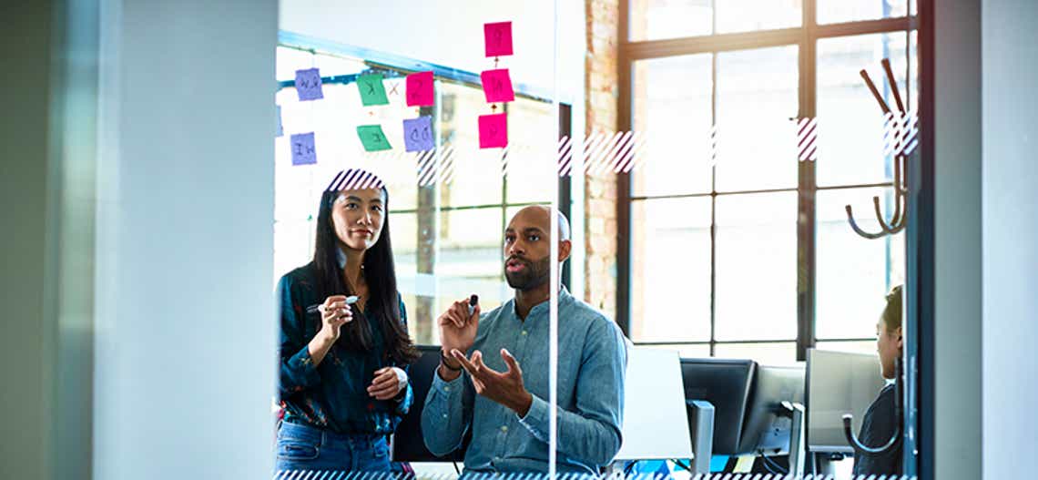 two sales enablement professionals outlining their sales enablement framework on a white board with post-its 