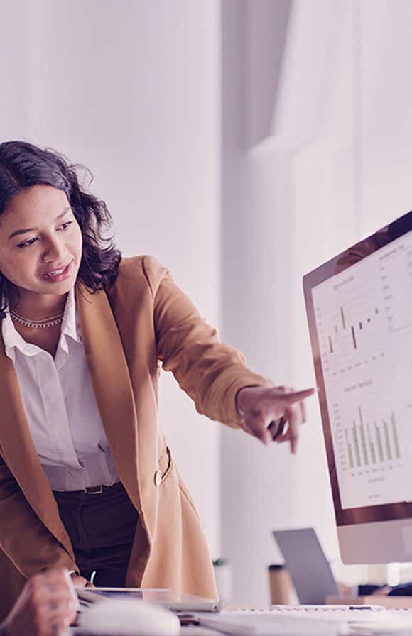 two sales managers looking at a desktop reviewing metrics that show the impact of sales training on their team's performance.