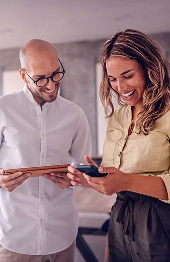 close of up two sales professionals with the rest of their team in the background working together in the positive sales culture the managers who participated in richardson's strengthening sales culture training module created.