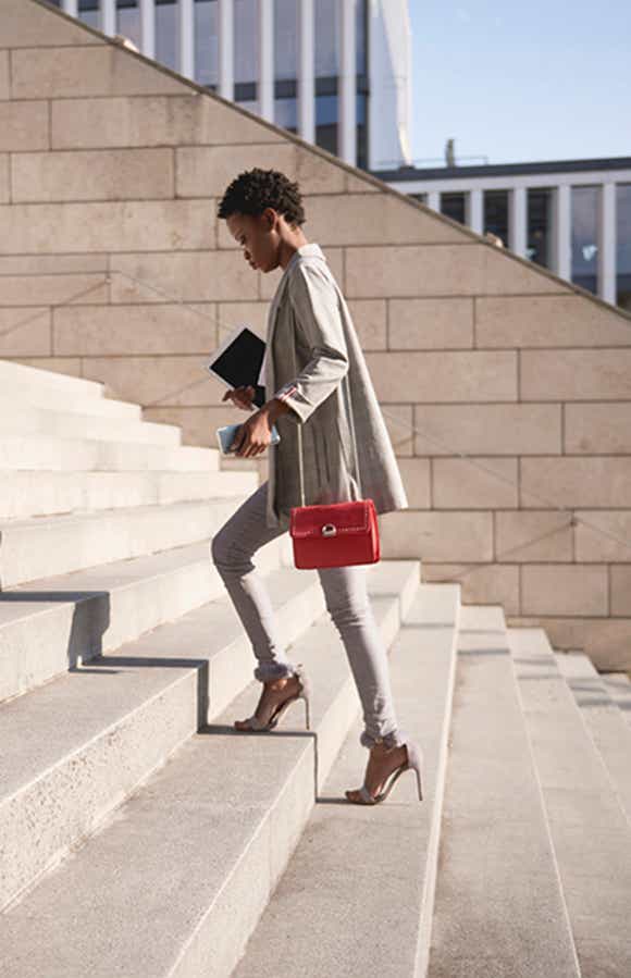 confident sales woman walking up the stairs on her way to a meeting with clients where she is going to use the Challenger approach to drive the deal forward